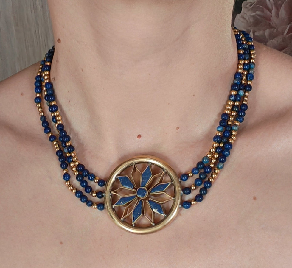 Necklace with blue beads and a gold rosette on a person's neck. sumerian style nec
