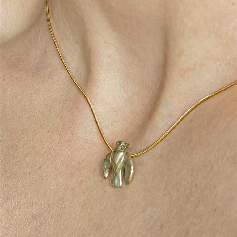 Gold necklace with a small eagle pendant on a person's neck
