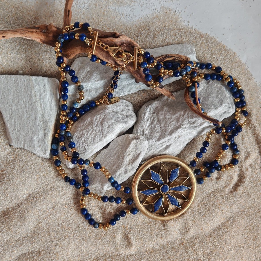 Jewelry with blue beads and gold accents on a sandy surface